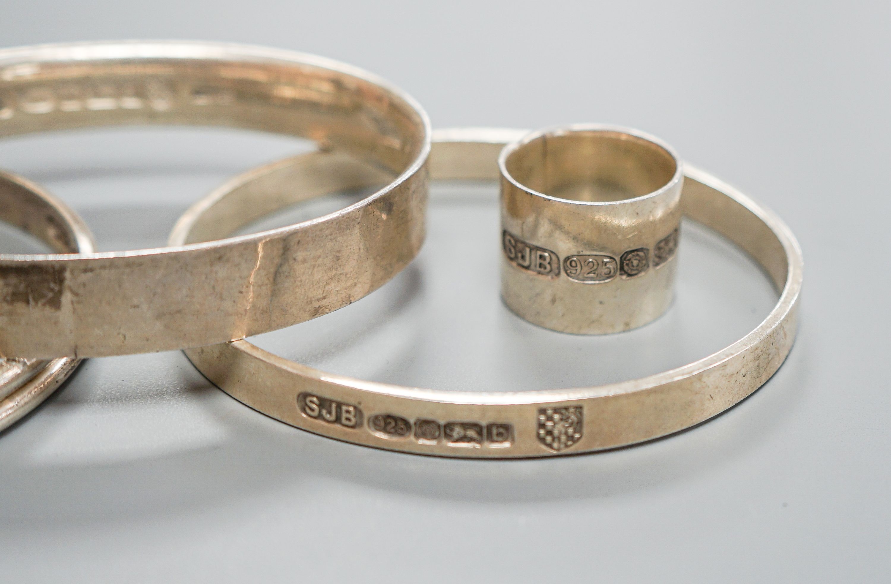 Three modern silver bangles and a large silver band, all by Simon J. Beer of Lewes
